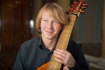 handsome  young musician play viola da gamba in palace