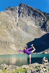 Girl doing yoga pose on a mountain lake