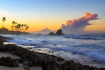 Fototapeta premium Sunrise at a rocky beach with purple clouds