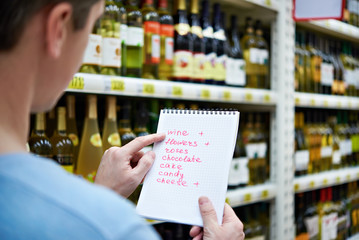 Man chooses bottle of wine for date in store