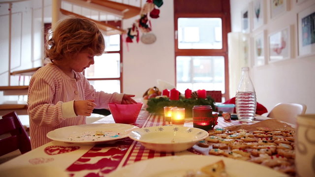 A little girl takes a nibble while icing cookies and treats on Advent Sunday. 