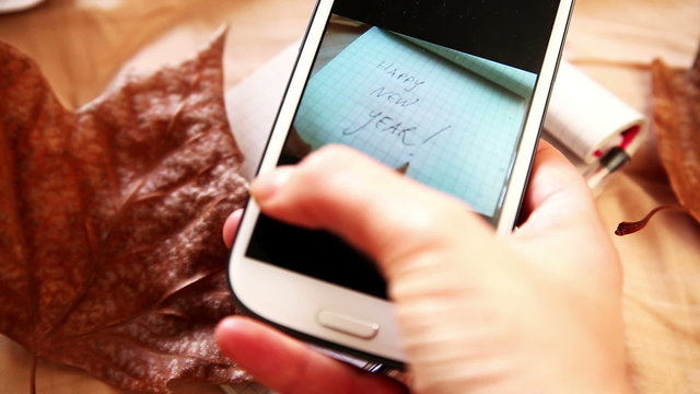 hands taking a picture of happy new year written on notebook to post on social network