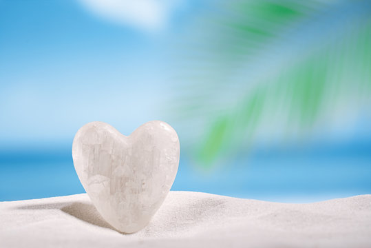 white crystal heart on white sand beach