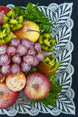 Fruits sprinkled with powdered sugar on a plate on a blue background