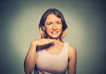 angry young woman gesturing with hand to stop talking, cut it out