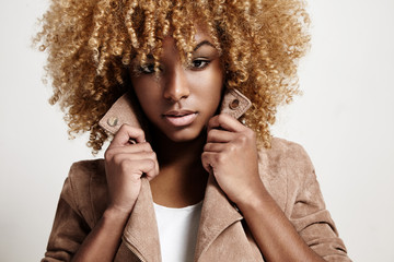 black woman wears beige jacket, curly hair