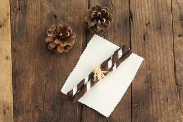 Pine cone and chocolate roll on wooden table