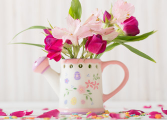 bouquet of bright flowers in watering can on wooden background