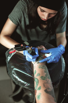 Beautiful brunette girl makes tattoo. Tattooist makes a tattoo. Closeup