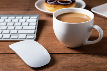 Obraz na płótnie Canvas Coffee cup with donut and computer