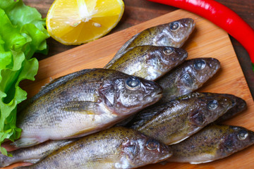 raw redfish ruff fish on the kitchen table with vegetables and lemon
