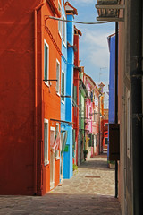 Narrow street with colorful apartment houses in Burano, Venice, Italy