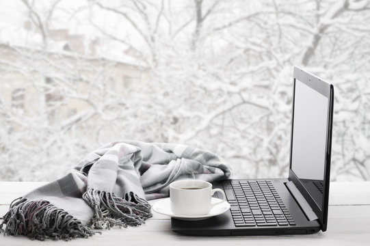 Laptop and coffee on winter window