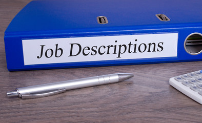 Job Descriptions blue binder on desk in the office with pen