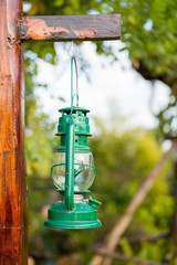 side view of green storm lantern on wood rack