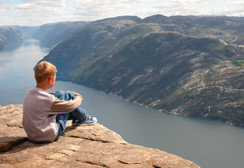 Naklejka na ściany i meble The boy thoughtfully looks afar, sitting on the edge of Pulpit R