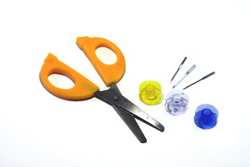 Spools, needles and scissors with orange handles isolated on white background