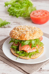 burger with smoked salmon and vegetables, close-up, vertical