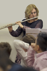 Flautist. Middle Aged woman playing flute instrument in school concert.
