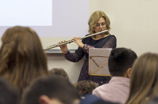 Flautist. Middle Aged woman playing flute instrument in school concert.