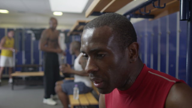  man in gym locker room rehydrating with water after a workout