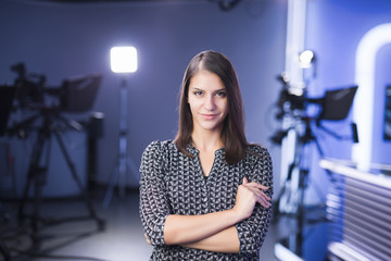 Young beautiful brunette television announcer at studio standing next to the camera.TV director at...