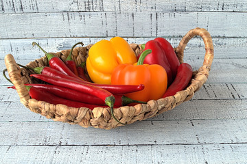  Pepper.  Bitter pepper red and yellow peppers in a wicker basket on a wooden background.
  