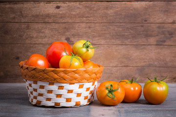 juicy red tomatoes in basket on wooden table