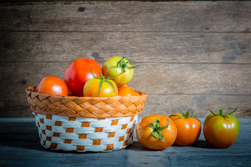 juicy red tomatoes in basket on wooden table