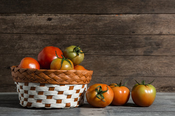 juicy red tomatoes in basket on wooden table