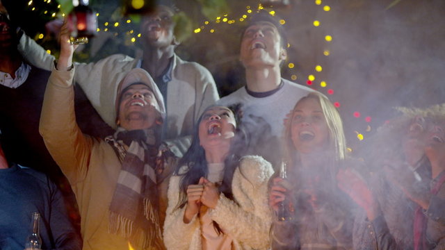  Happy Mixed Ethnicity Friends Watching Fireworks In Front Of Open Fire