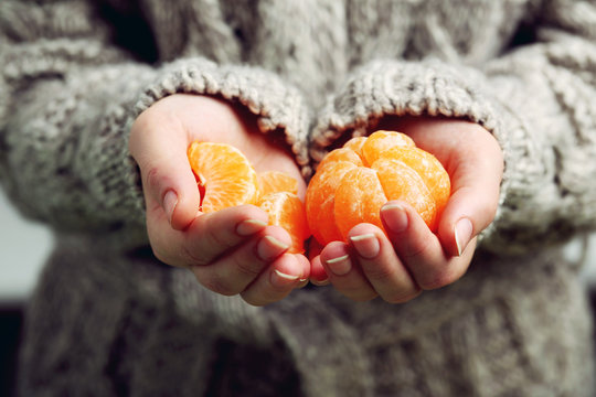 Female hands holding ripe mandarins, close up