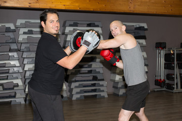 Portrait of two boxing men exercising together at fitness center