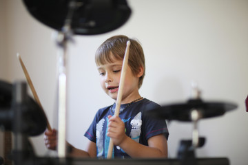 Child in rhythm of rock music, playing drums