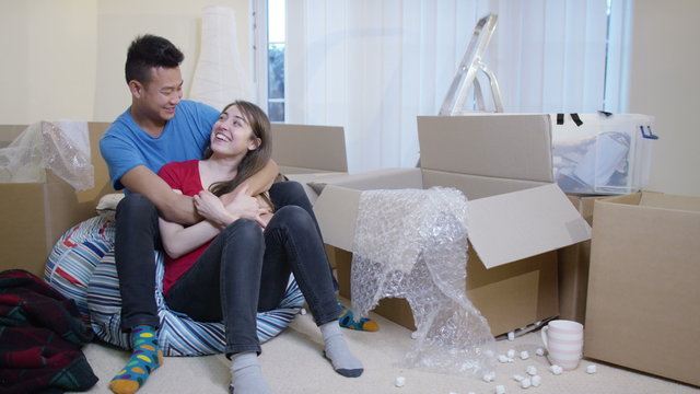  Happy young couple sitting amongst cardboard boxes with key to new home