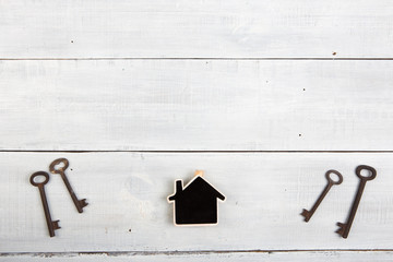 Real estate concept - little house and keys on white wooden desk
