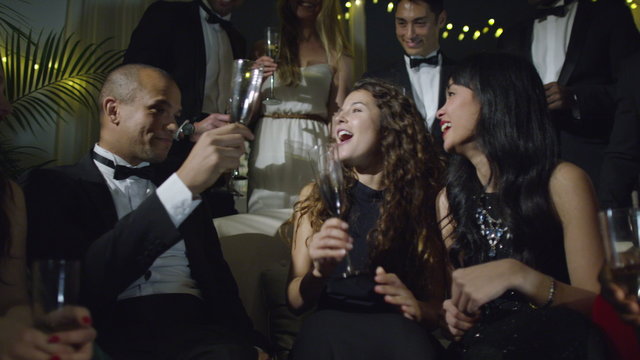  Happy group of friends at glamorous party, drinking champagne and celebrating