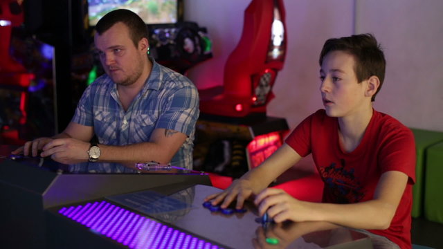 Father and son playing on slot machine simulator