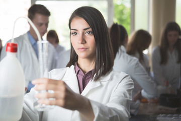 Fototapeta premium Scientific researcher holding a distilled purified deionised water in plastic bottles with a pump. Measuring graduated cylinder for measuring water volume.. Water for chemical solutions