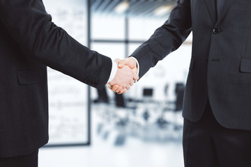 Business partners shake hands in modern conference room