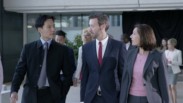  Large diverse business group talking as they walk through office building
