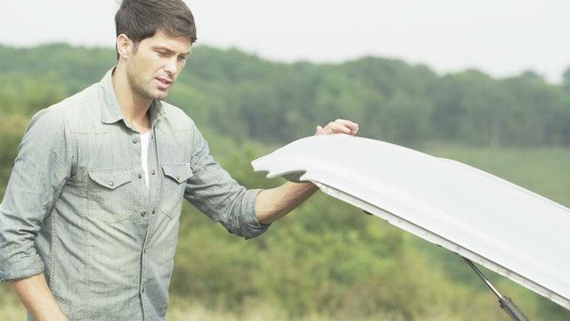  Stranded man with broken down car looks under the bonnet