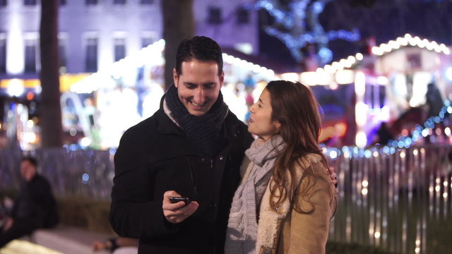 Happy romantic couple pose to take a selfie at Christmas fair. Shot on RED Epic.
