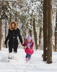 Fototapeta na wymiar Mom and daughter running in a forest through the snow