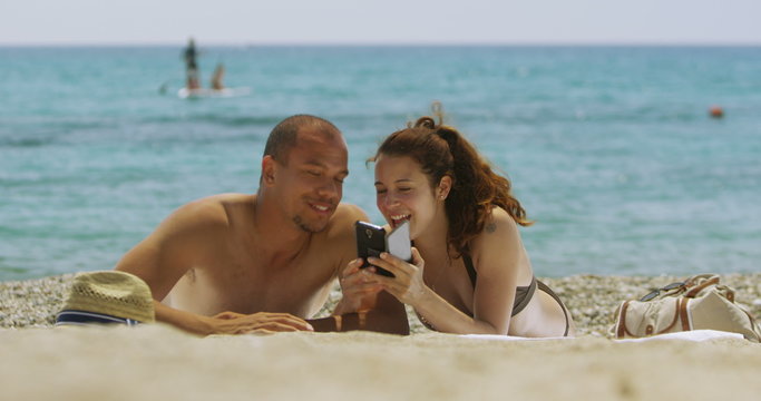  Happy couple relaxing at the beach posing for a photo with camera phone. 