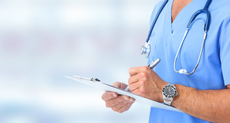 Doctor hands writing on a clipboard.
