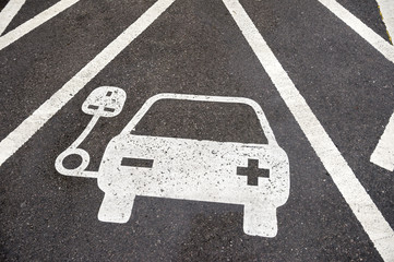 Electric vehicle charging station sign in a parking bay painted on black asphalt