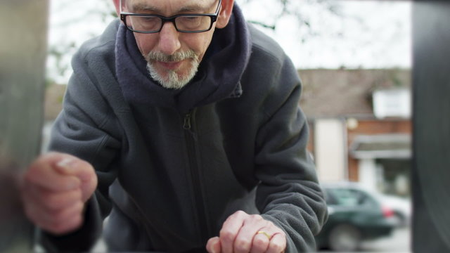Cautious man keeps checking behind him as he takes money from ATM machine