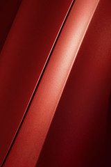 Surface of red sport sedan car, detail of metal hood and fender of vehicle bodywork 