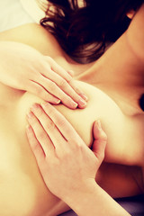 Woman examining breast on bed.